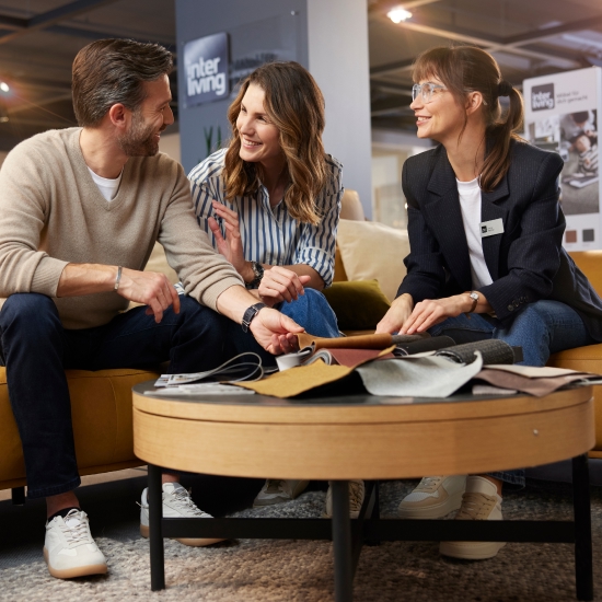 Ein Pärchen lässt sich bei Möbel Weber individuell zu Interliving Möbeln beraten. Drei Personen sitzen in einem gemütlichen Raum und besprechen die besten Einrichtungsmöglichkeiten.